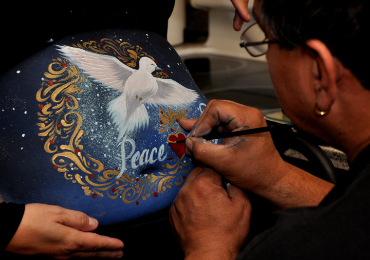 mark painting a white dove on the belly of a pregnant woman